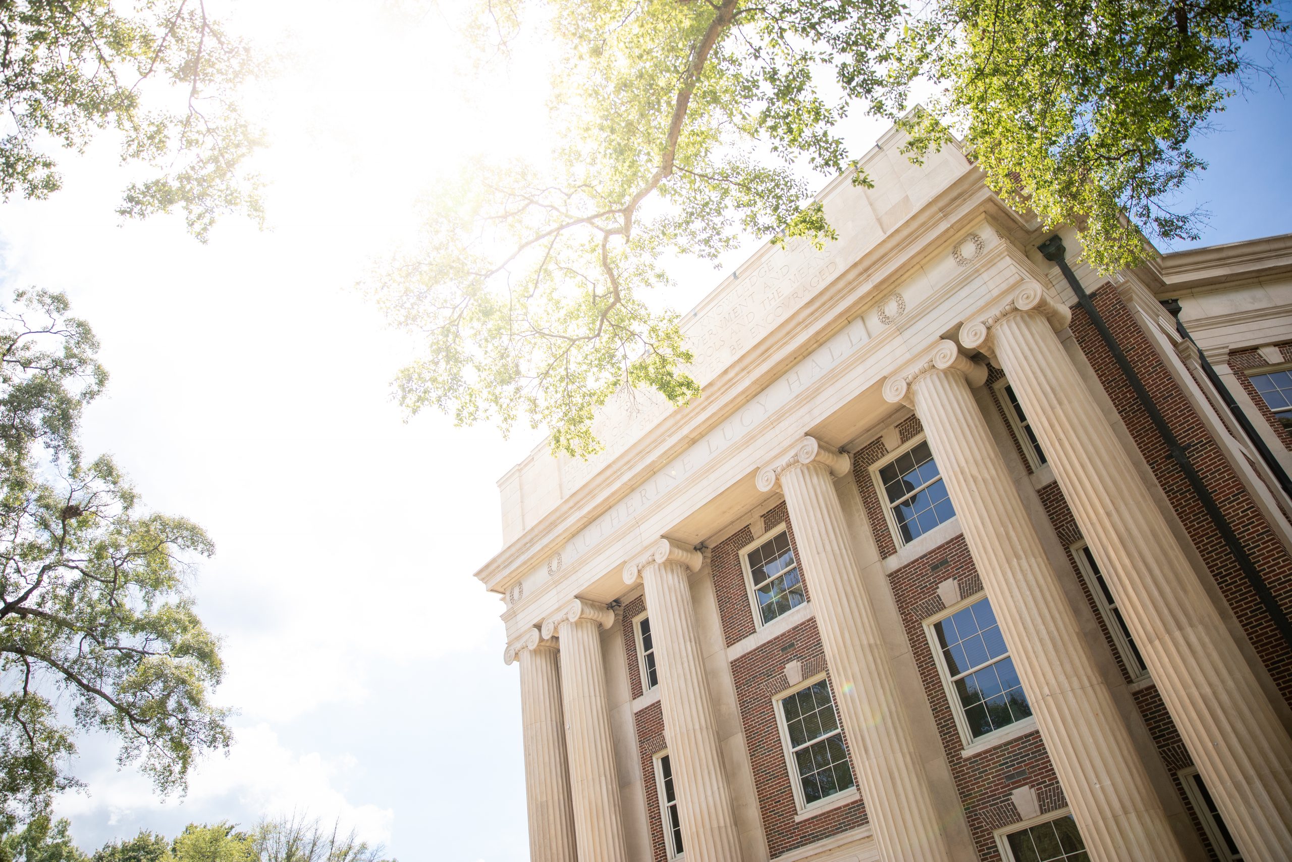 Autherine Lucy Hall Building with trees and sun shining